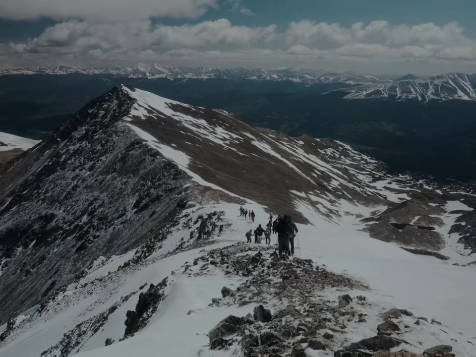 Climbers strung out along a long snowy ridge