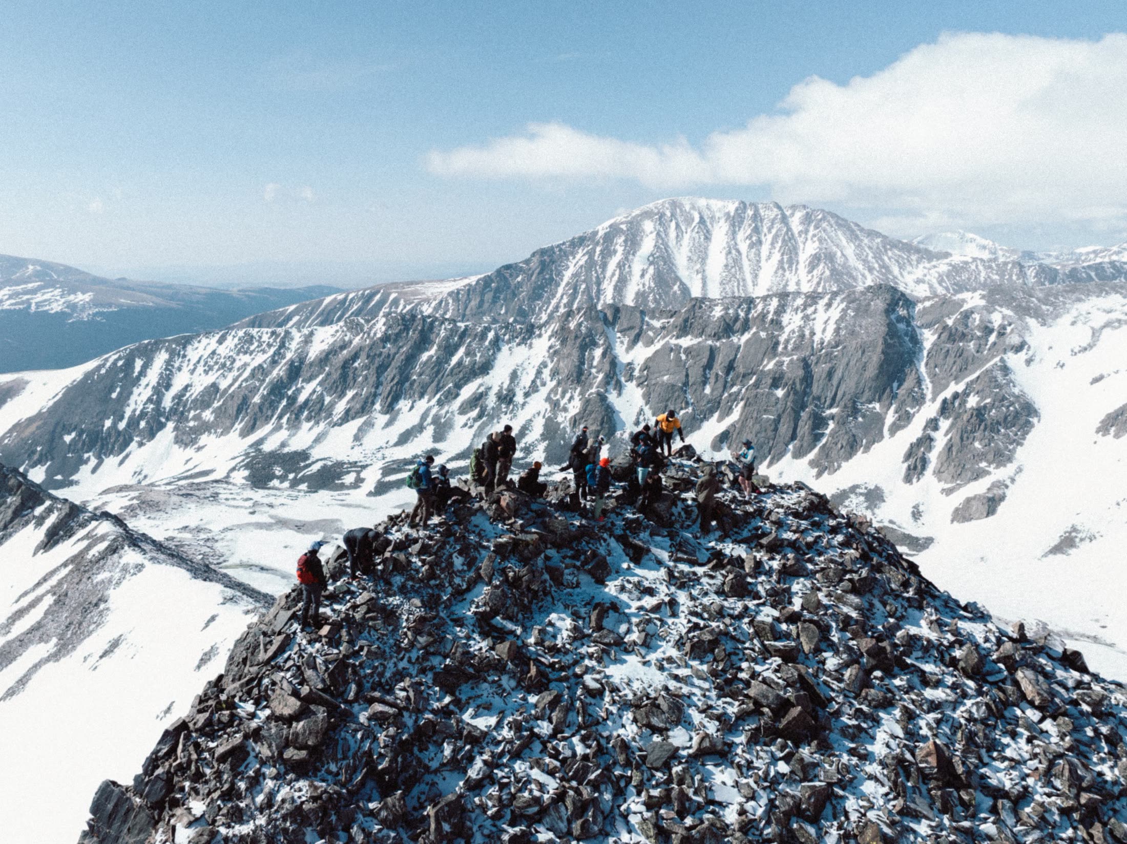 The crew gathered on Crystal Peak's rocky summit with snowy peaks behind