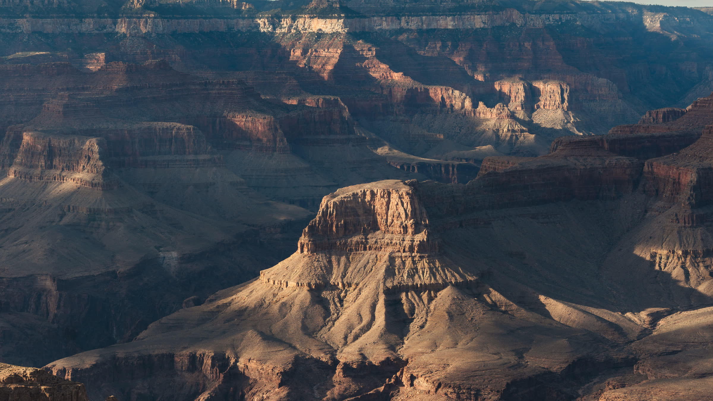 A sunlit butte rising from the layered walls of the Grand Canyon