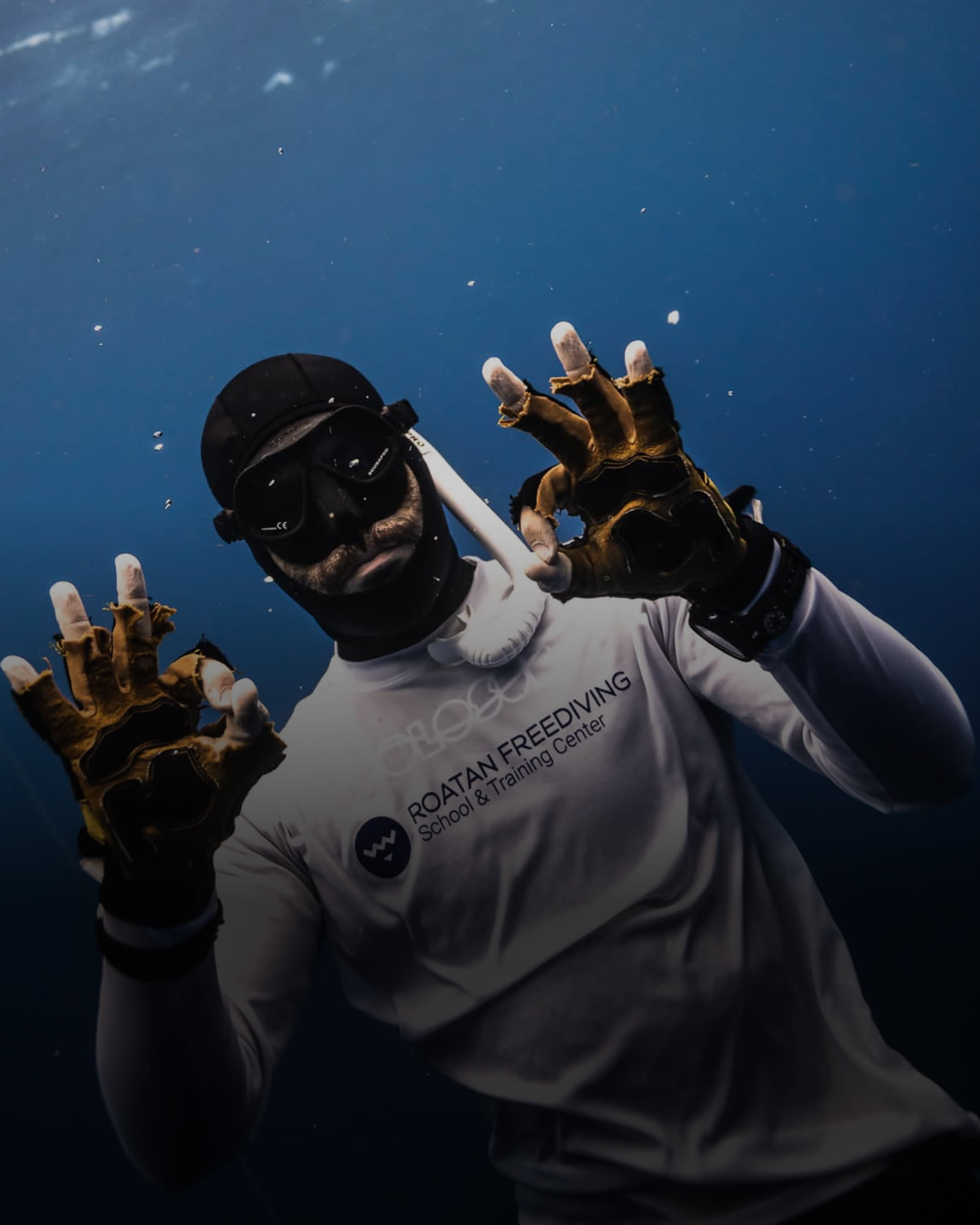 A freediver underwater raising both hands