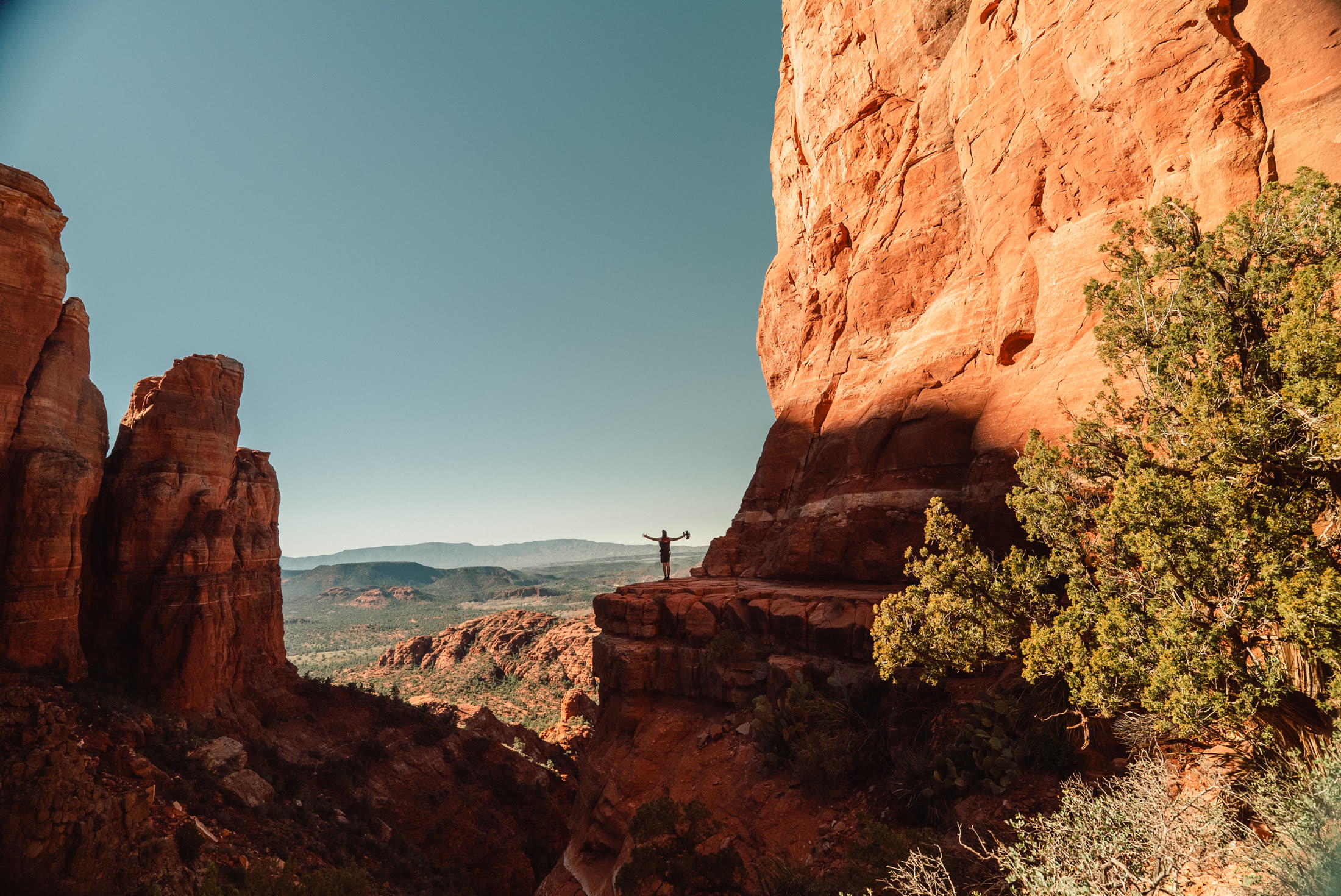 A lone figure on a ledge between red rock walls