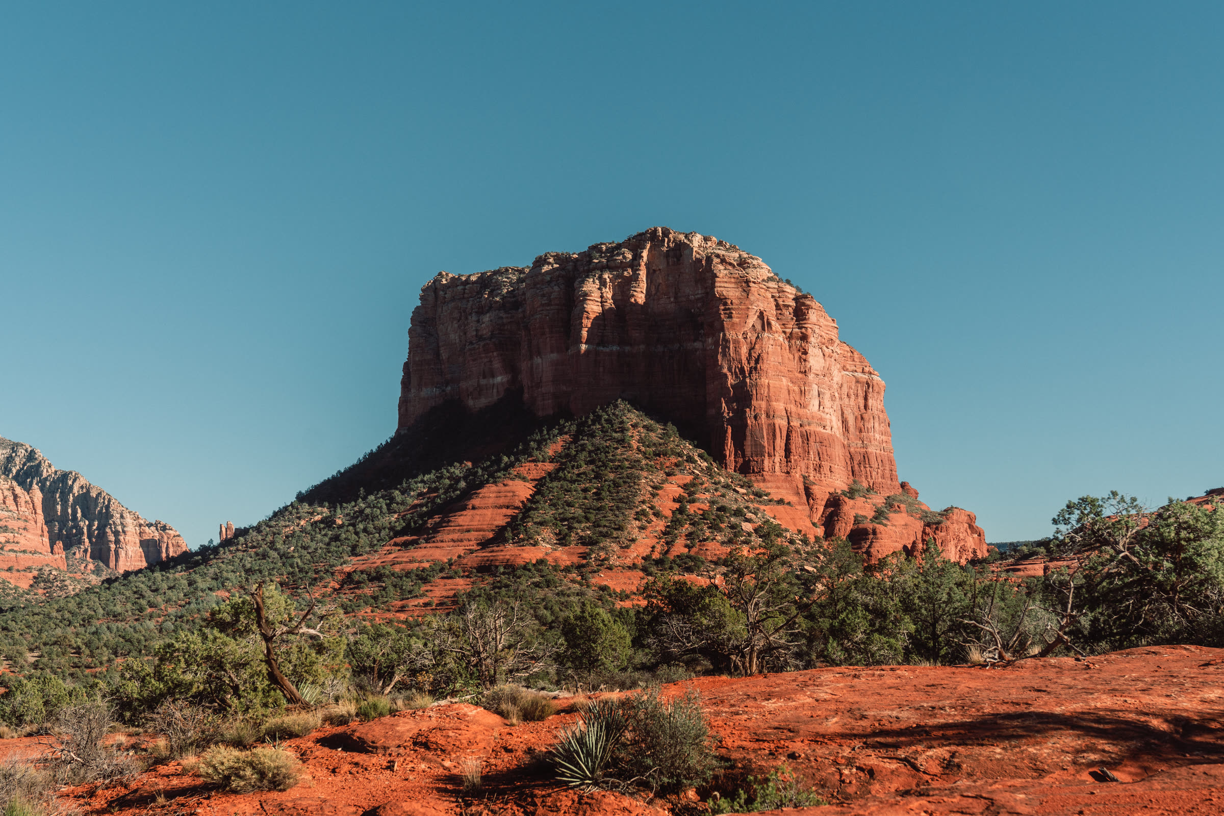 Courthouse Butte rising above red earth and juniper