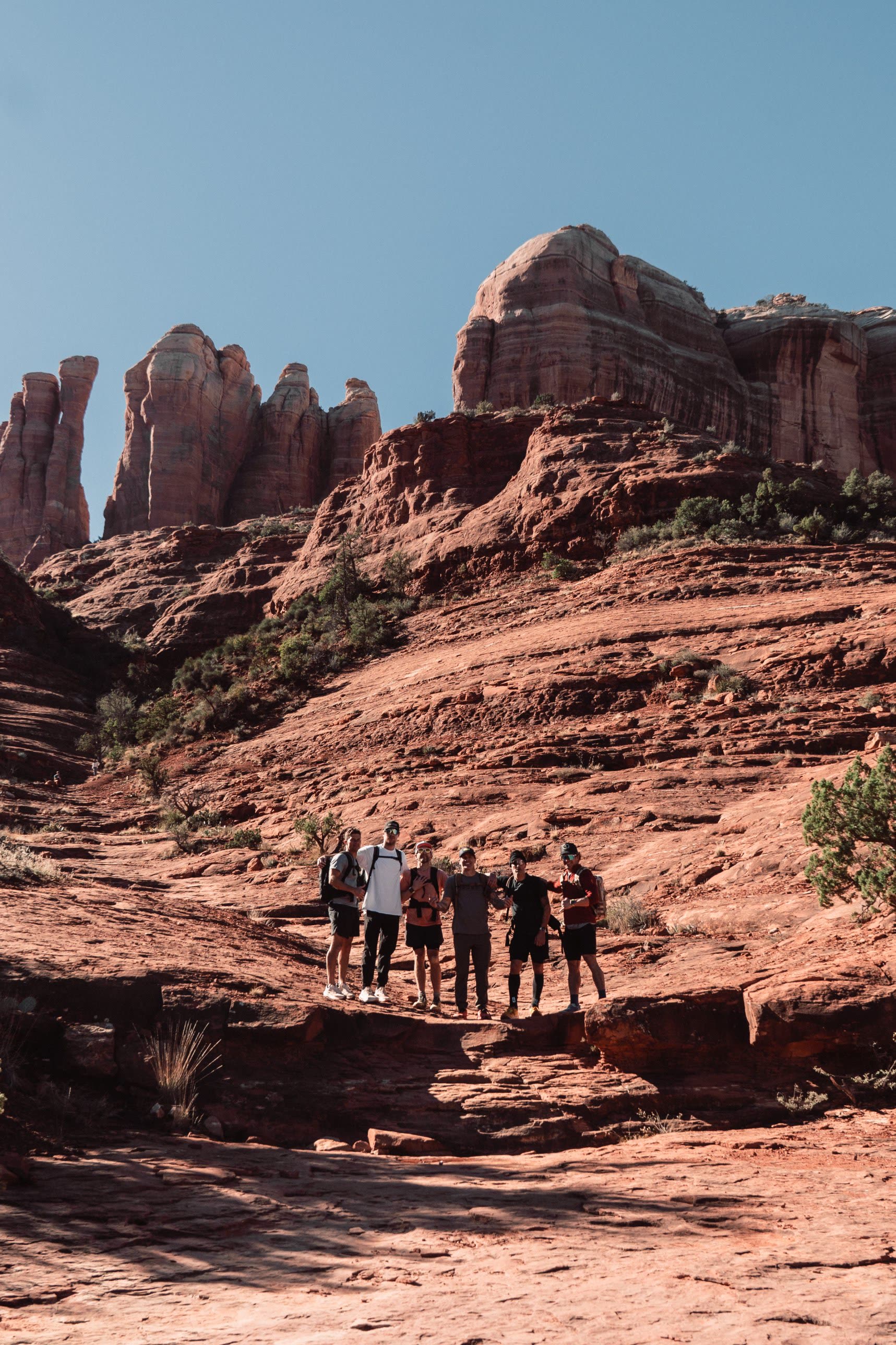 A crew standing together on slickrock beneath the Cathedral Rock spires