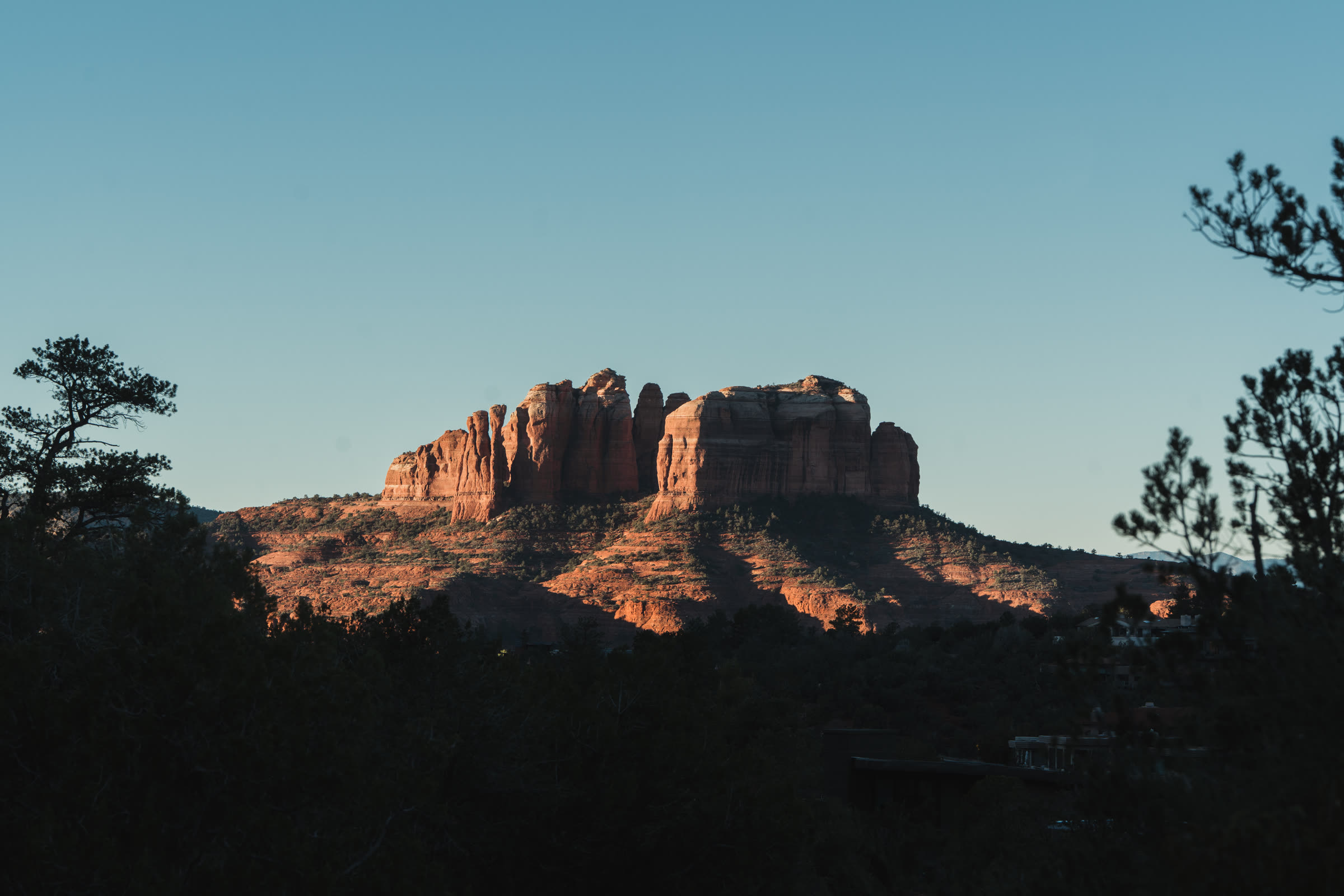 A red rock butte lit gold at first light above dark pines